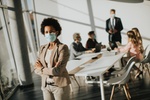 African American woman standing in the office and wear mask as protection from corona virus