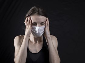 Frau mit Maske und Kopfweh