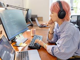 Frau mit pinken Haaren vor dem Bildschirm