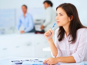 Frau mit Stift in der Hand blickt nachdenklich "in die Ferne"