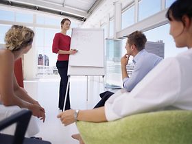 Frau präsentiert vor Gruppe am Flipchart