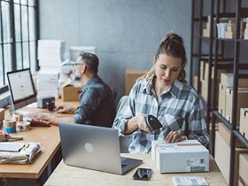 Frau scannt Paket im Versandbüro