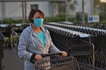 Frau schiebt Einkaufswagen mit Mundschutz