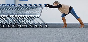 Frau schiebt Reihe von leeren Einkaufswagen