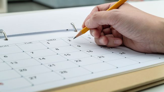 Frau schreibt in den Kalender