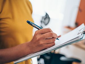 Frau schreibt mit Stift auf Papier