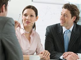 Frau sitzt im Buero bei Besprechung zwischen Maennern
