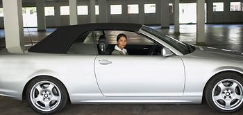 Frau sitzt in silberfarbenem Cabriolet im Parkhaus