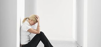 Frau sitzt niedergeschlagen an Gang auf Boden