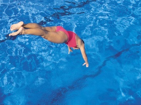 Frau springt in Schwimmbecken