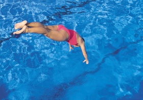 Frau springt in Schwimmbecken
