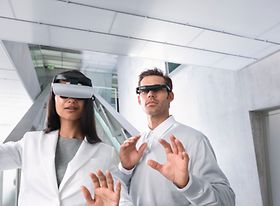 Frau und Mann stehen mit Videobrillen in Buero