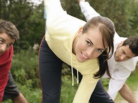 Frau und zwei Maenner bei Gymnastik im Freien