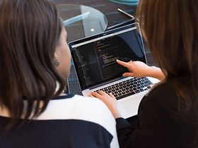 Frau zeigt einer anderen Frau etwas auf dem Laptop