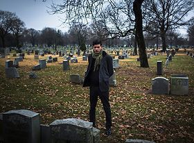 Friedhof mit Mann der auf einen Grabstein blickt