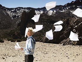 Gegenwind Mann Blätter Papier Landschaft karg