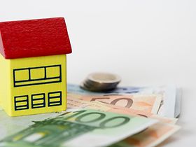 Gelbes Modellhaus auf Geldscheinen