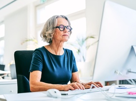 Confident businesswoman using computer at desk. Mature female professional is working in creative of