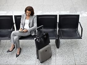 Geschäftsfrau macht Notizen am Flughafen mit Gepäck