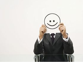 Geschäftsmann hält sich ein Blatt mit Smiley vor das Gesicht