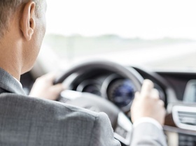 Geschäftsmann in Anzug am Steuer