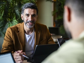 Business professional in his 30s holding pen and looking towards co-worker