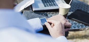 Geschäftsmann schaut in Café auf Smart Watch