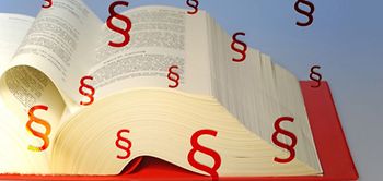 Gesetzbuch aufgeschlagen Paragrafen rot fliegen