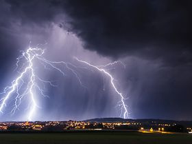 Gewitterfront mit Blitzen über Stadt