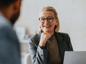 Smiling senior businesswoman in glasses conversing with a colleag