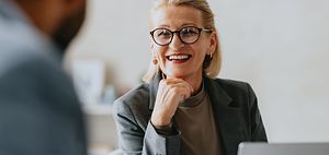 Smiling senior businesswoman in glasses conversing with a colleag