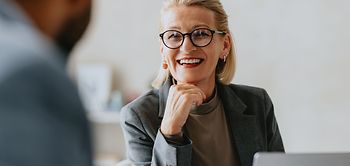 Smiling senior businesswoman in glasses conversing with a colleag