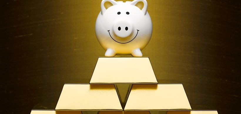 glückliches Sparschwein auf Goldbarren