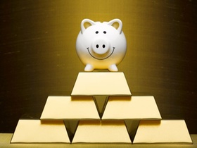 Smiling piggy bank on top of stacked gold bars