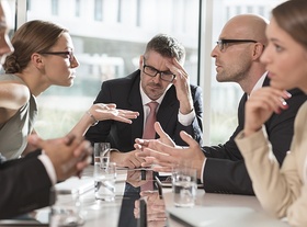 Gruppe von Leuten streitend an einem Konferenztisch