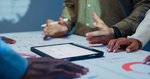 Close-up group of business working late, analyzing financial reports and charts on digital tablet su