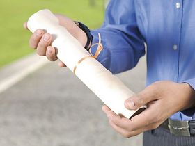 Haende halten aufgerollte Abschlussurkunde