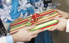 Hände übergeben Geschenk vor Weihnachtsbaum