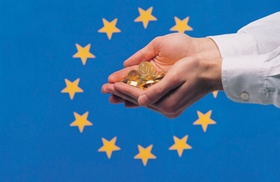 Hände voller Münzen vor EU-Fahne