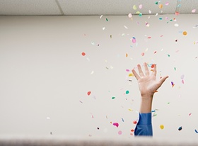 Hand die Konfetti in die Luft wirft