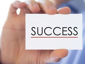 Hand hält Karte mit Aufschrift Success in die Kamera