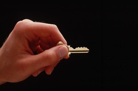 Hand mit Schlüssel vor dunklem Hintergrund