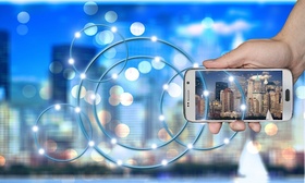 smart city-Hand die Smartphone hält vor verschwommener Silhouette einer Großstadt