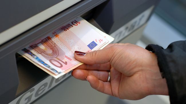 Hand nimmt Geld aus Geldautomat