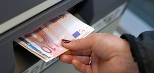 Hand nimmt Geld aus Geldautomat