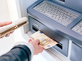 Hand zieht 50 Euronoten aus dem Bankautomaten