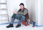 Handwerker sitzt auf Baustelle bei Pause auf Werkzeugkasten