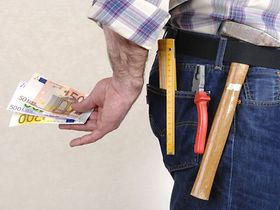 Handwerker versteckt Geld hinter seinem Rücken