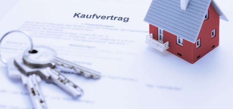 Hausmodell und Schluessel auf Kaufvertrag