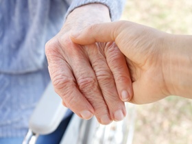 Caregiver holding senior lady's hand